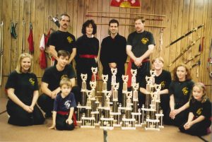 Team photo with a large collection of tournament trophies