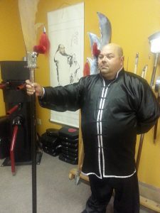 Student with fist extended in a strike, weapons rack behind