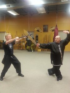 Two students sparring with weapons raised