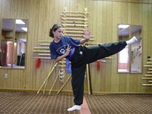 Student mid high side-kick, arms extended for balance