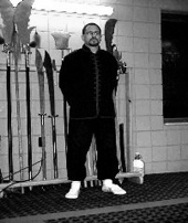 Student standing at attention before the weapons rack, black and white photo
